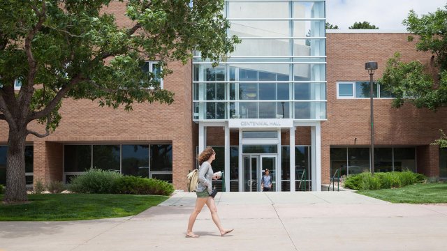 student walking past the main entrance to Centennial Hall