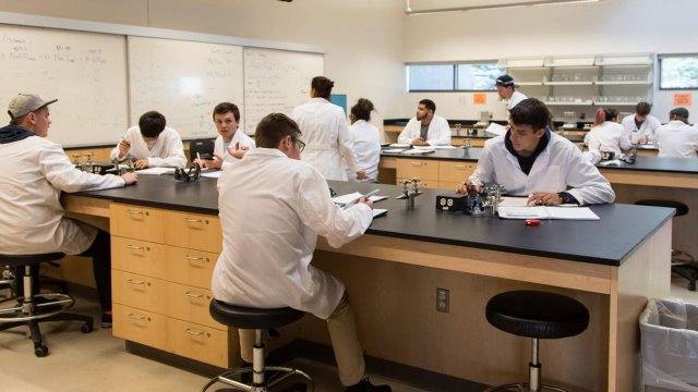 students in white lab coats participating in a class