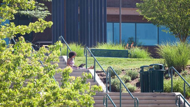 student sitting on the steps of the EAS building with a laptop