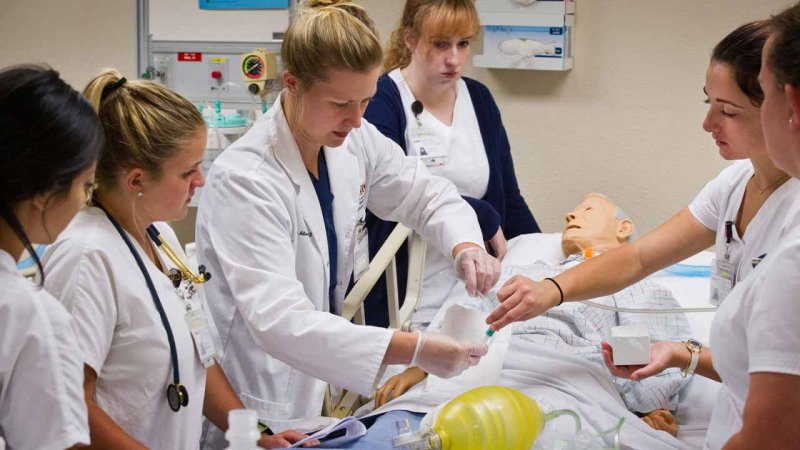 nursing students working together in a lab on a human medical simulator