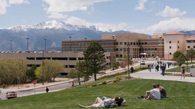students relaxing on the lawn at El Pomar Plaza with a view of the mountains
